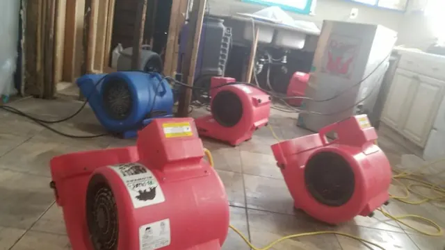 Blue and red air movers set up to dry a tiled floor